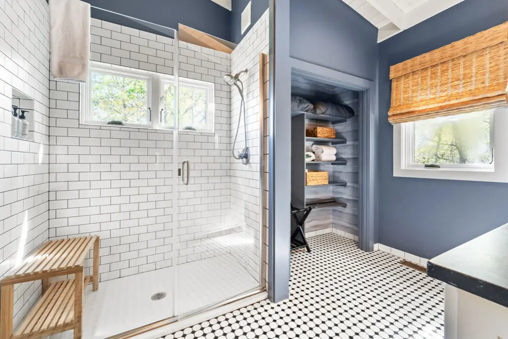 Bathroom with subway tile shower, penny tile floor, and linen closet.