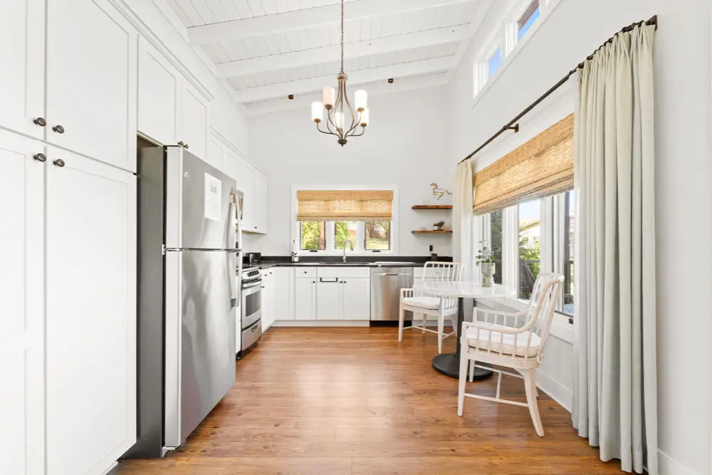 Kitchen with wood floors, stainless steel appliances, and a small dining area.
