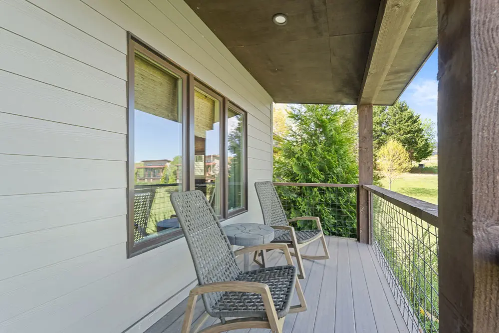 Relaxing rocking chairs on a modern deck overlooking a green lawn.