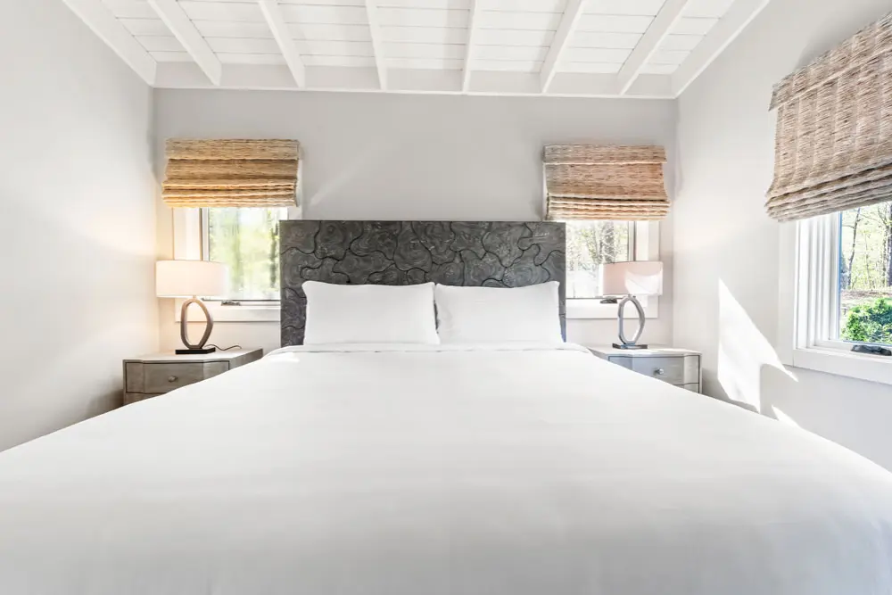 Bedroom with a gray headboard, white bedding, and natural light. 