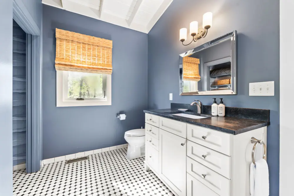 Bathroom with white vanity, dark countertop, and black and white checkered floor.