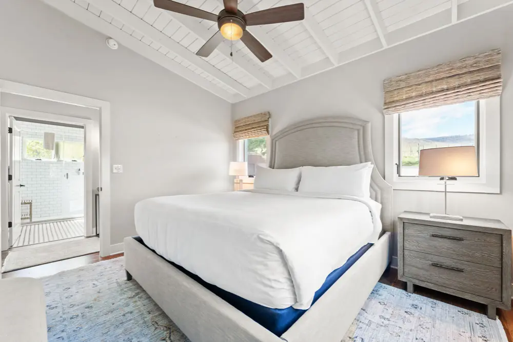 Bedroom with a comfortable queen-size bed,  wood nightstand, and window view.