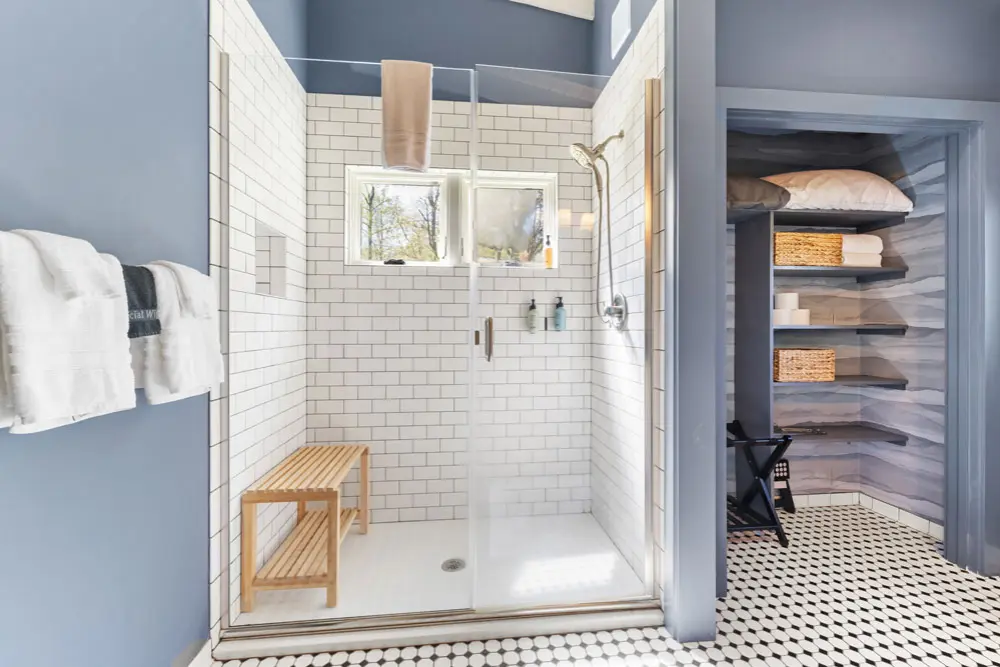 Bathroom with subway tile shower, glass enclosure, and linen closet.