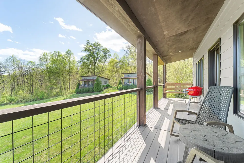 Cabin porch with mountain view, grill, and rocking chair.