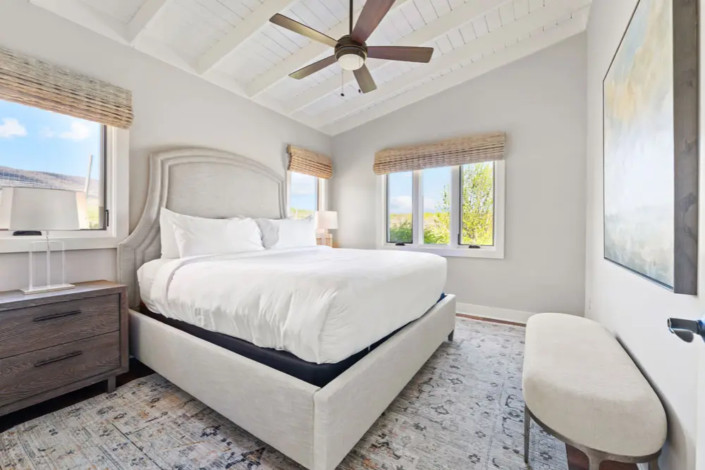 Bedroom with king-size bed, white linens, and mountain views.