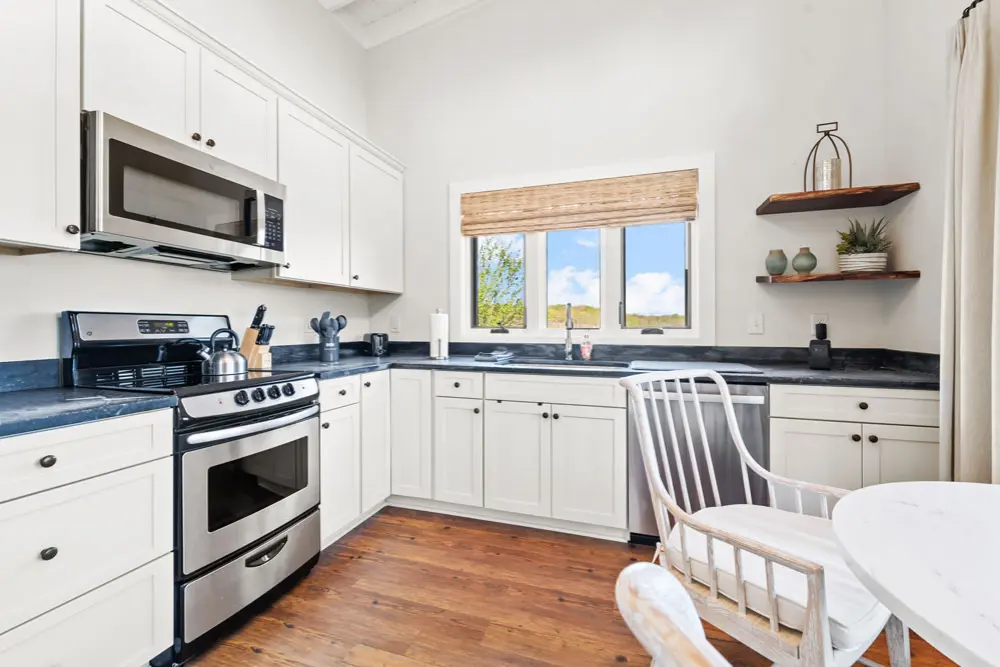 Kitchen with white cabinets, stainless steel appliances, and a farmhouse-style chair.