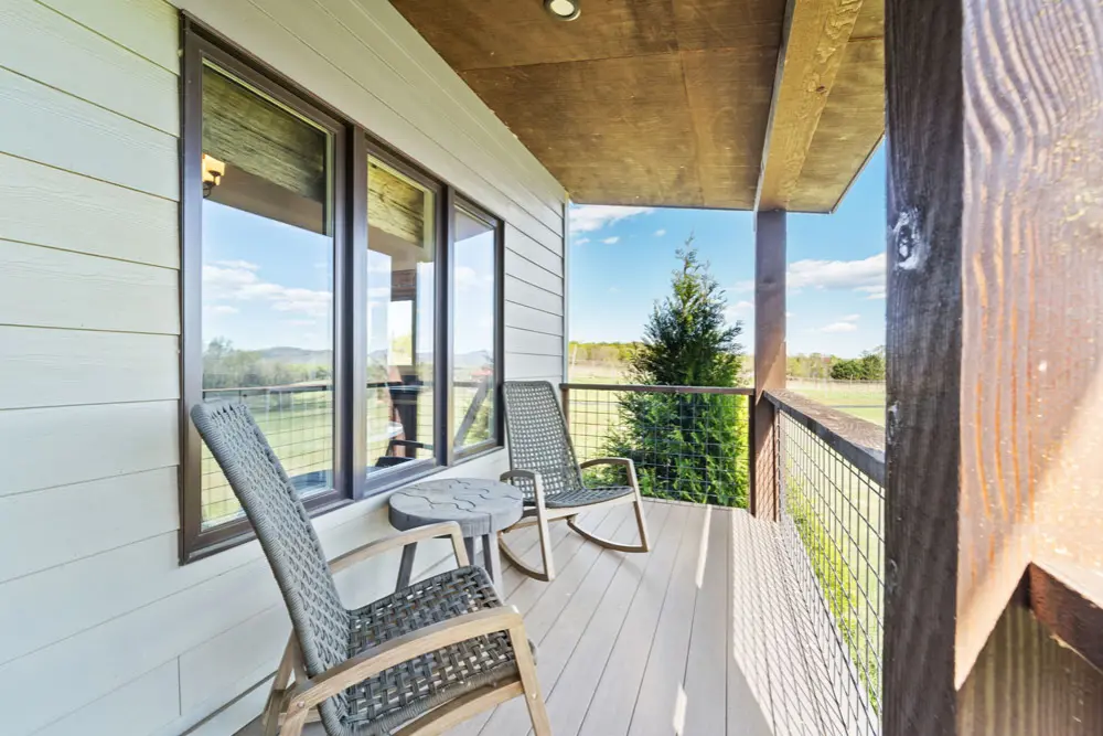 Two rocking chairs on a deck overlooking a scenic view.