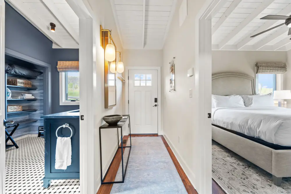 Hallway with white walls, hardwood floors, and a view into a bedroom and laundry room.