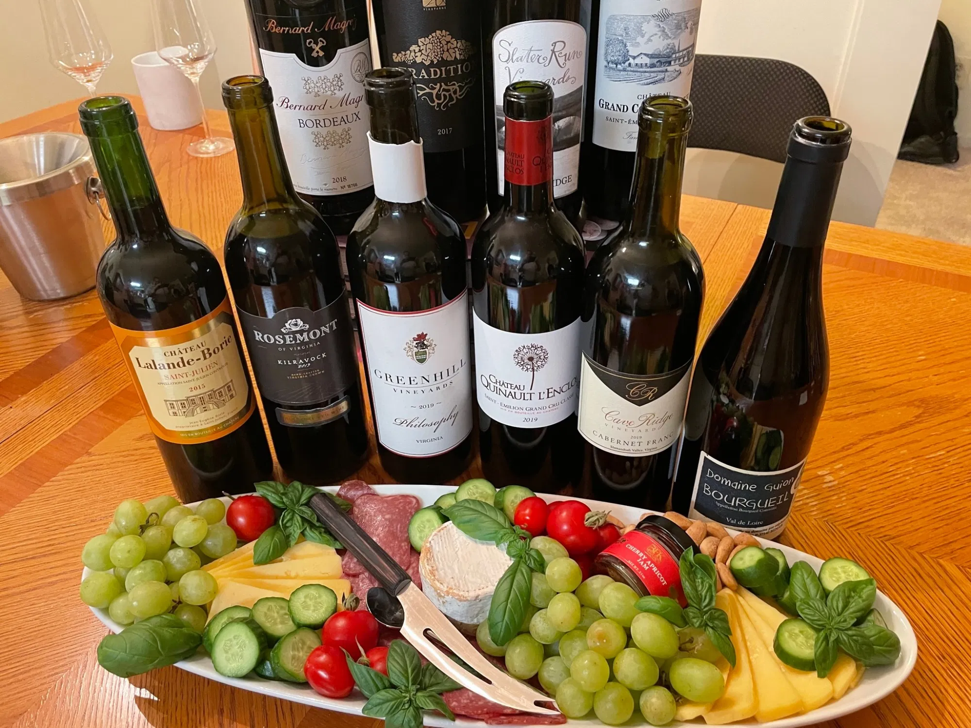 Bowl of fruits and cheese with bottle of wines.